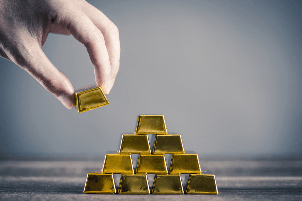 Person stacking gold bars representing investing in gold