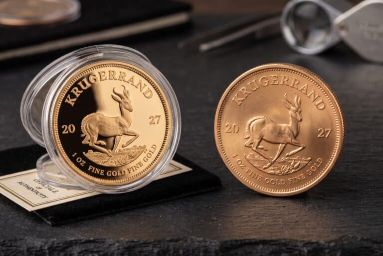 A proof Krugerrand 1 oz gold coin in a clear capsule resting on a certificate of authenticity, next to a standard bullion Krugerrand standing on its edge, with a jeweler's loupe and tweezers on a dark slate surface.